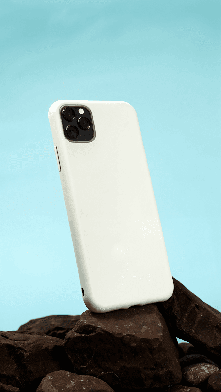 White smartphone on rocks against a pale blue backdrop
